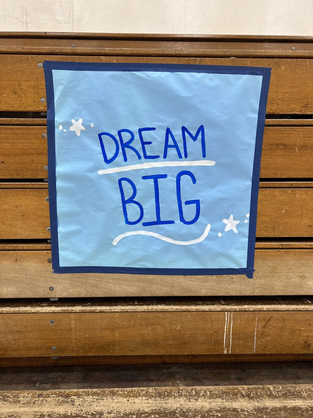 Dream Big poster framed with blue Mascot Tape on gym bleachers