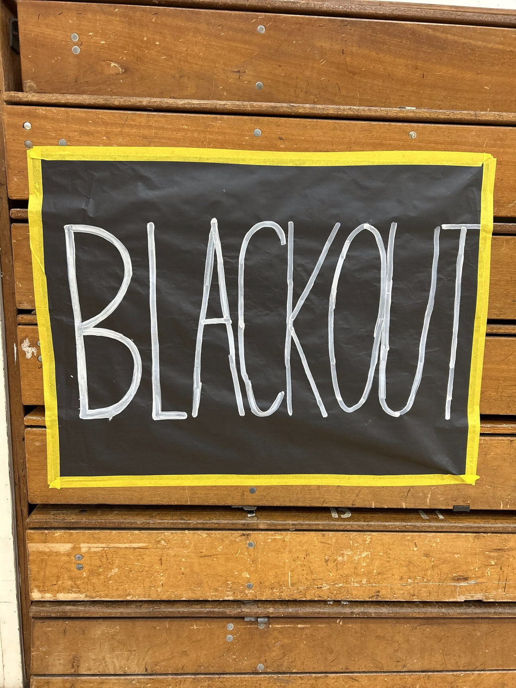 Blackout spirit poster framed with yellow Mascot Tape border in a school gym